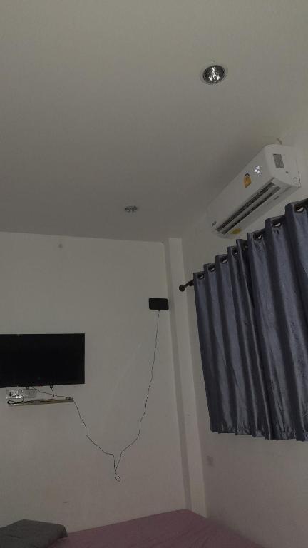 sala de estar con TV y cortina en บ้านพัก, en Ban Bang Pho