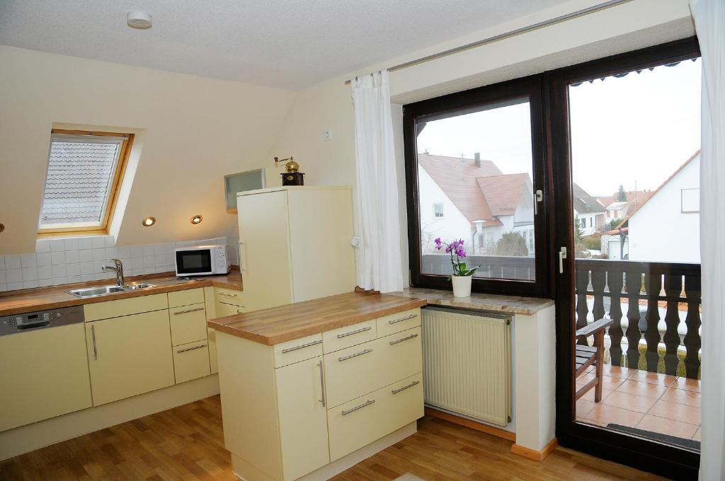 a kitchen with white cabinets and a large window at Gabis-ferienwohnung in Munningen