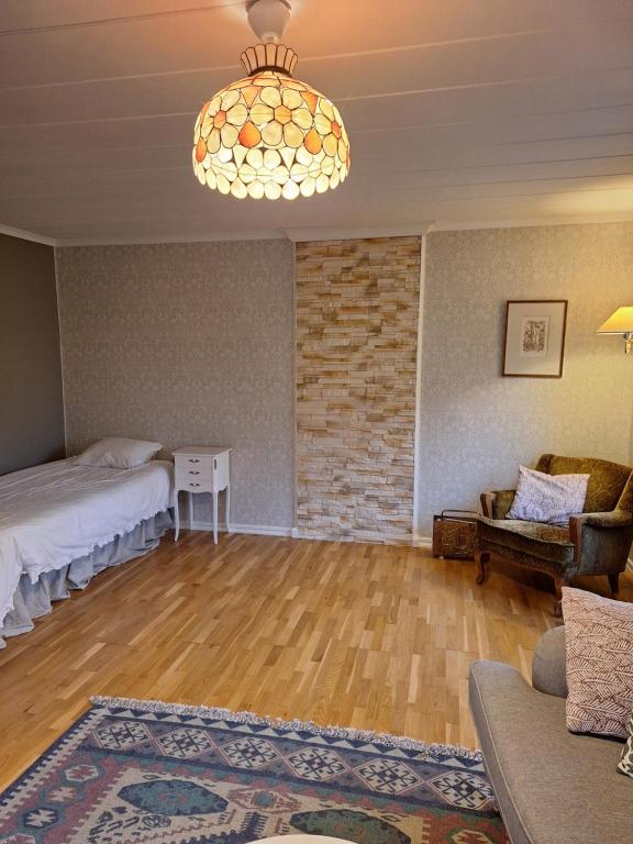 uma sala de estar com uma cama e um lustre em Fin torparstuga strax utanför Falköping. em Falköping