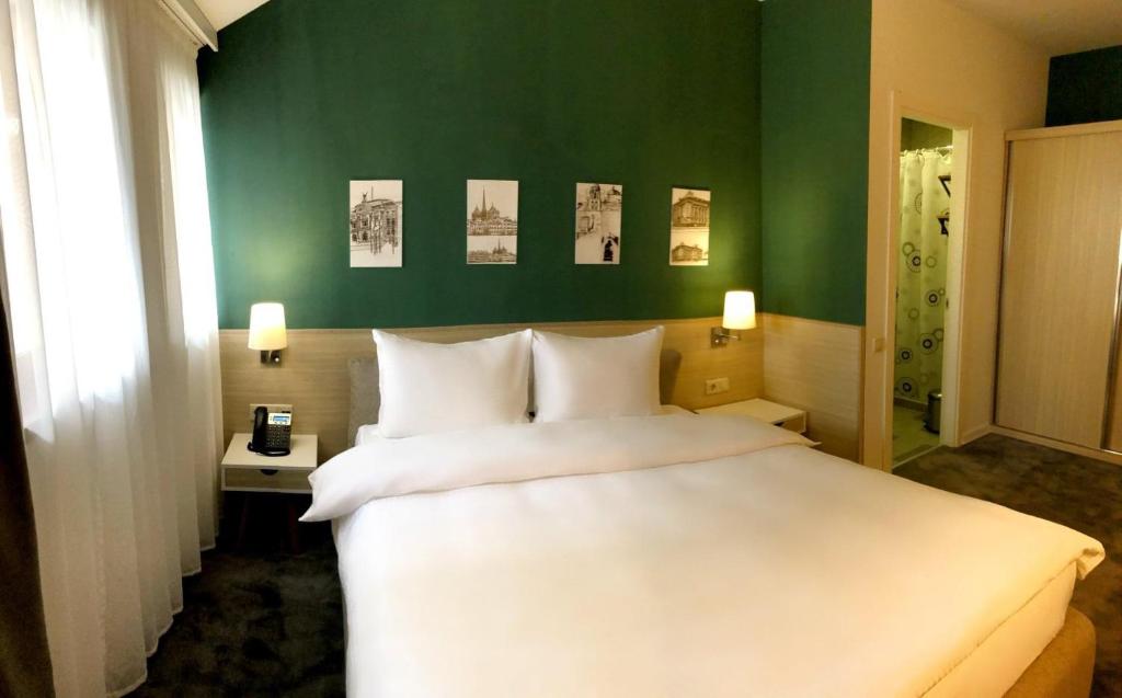 ein Schlafzimmer mit einem weißen Bett und einer grünen Wand in der Unterkunft Hotel In City in Yerevan