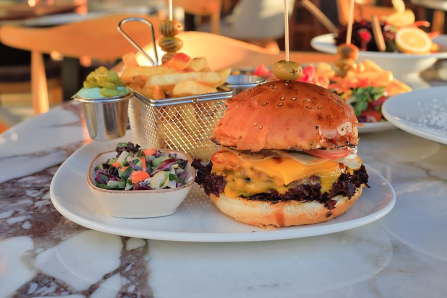 a plate of food with a cheeseburger and a salad at west coast boutique hotel in Bodrum City