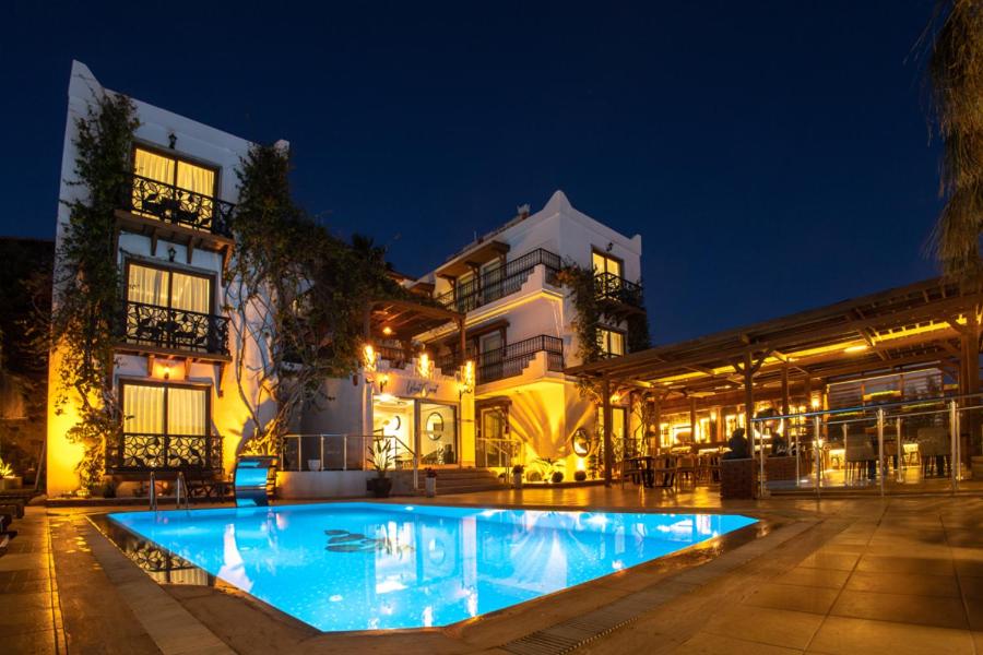 a large building with a swimming pool at night at west coast boutique hotel in Bodrum City