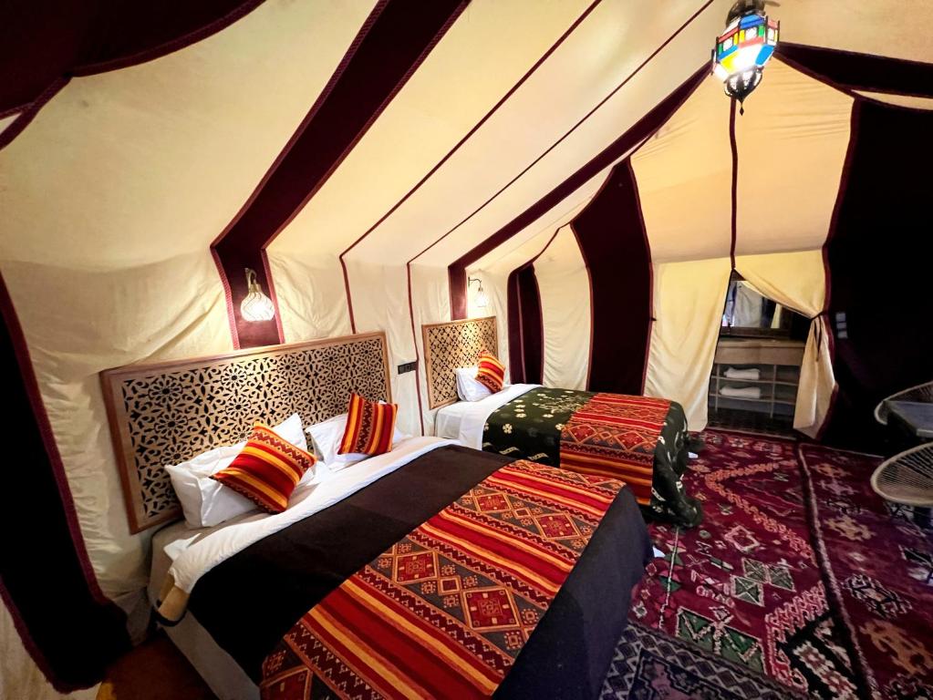a bedroom with two beds in a tent at Hotel ksar merzouga in Merzouga