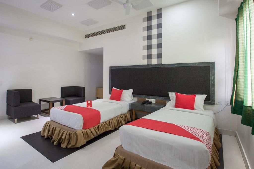 um quarto de hotel com duas camas e uma cadeira em OYO Hotel Palak Residency Near Erragadda Metro Station em Ameerpet