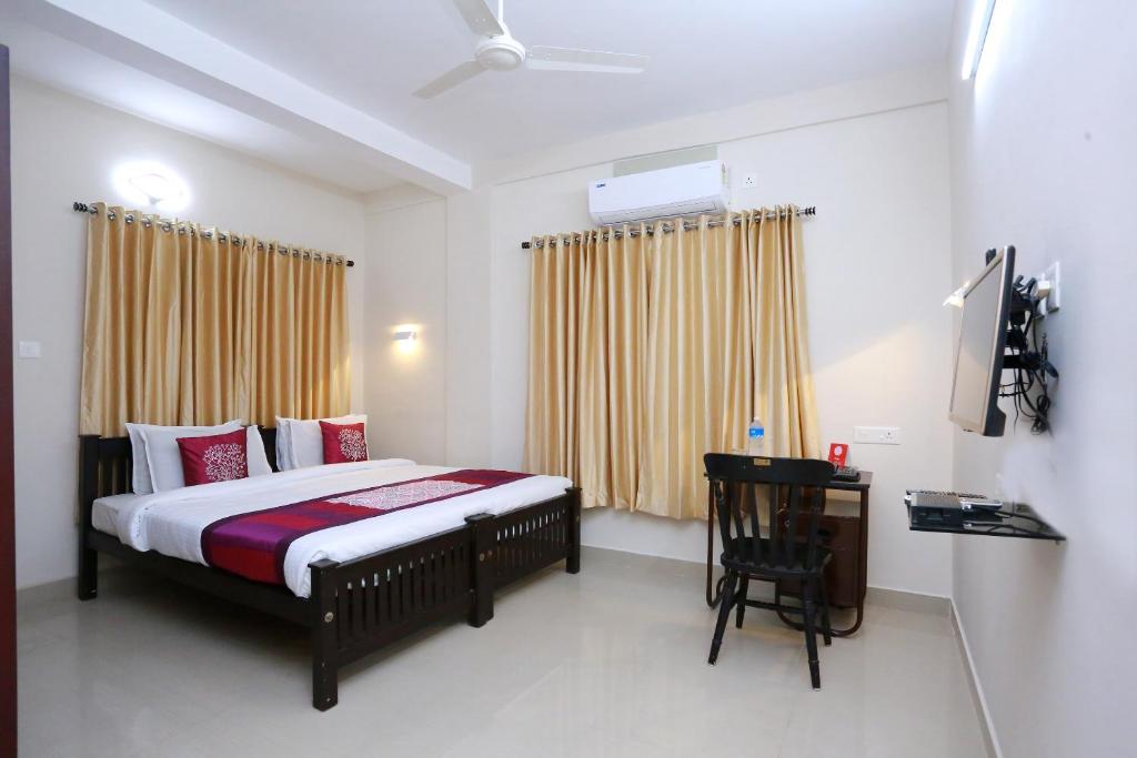 1 dormitorio con cama y escritorio. en OYO Chaithanya Complex en Muttam