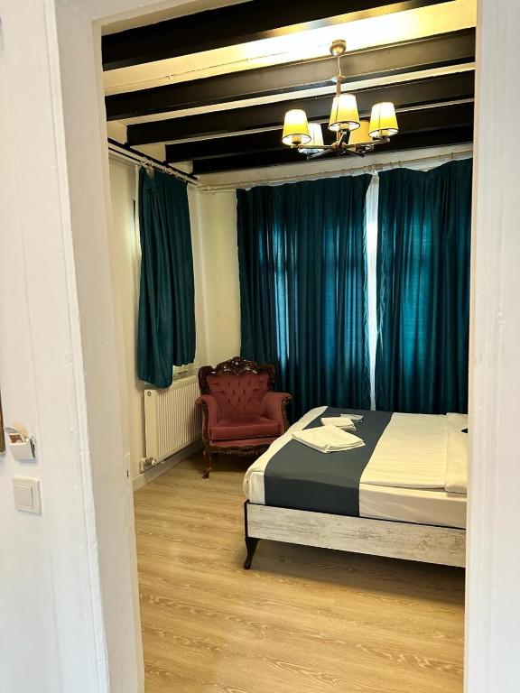 ein Schlafzimmer mit einem Bett mit blauen Vorhängen und einem Stuhl in der Unterkunft VOLGAİSTANBUL in Istanbul