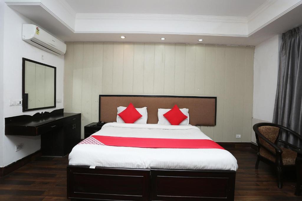 um quarto com uma cama grande e almofadas vermelhas em Super OYO The Avenue Residency Near Leisure Valley Park em Gurgaon