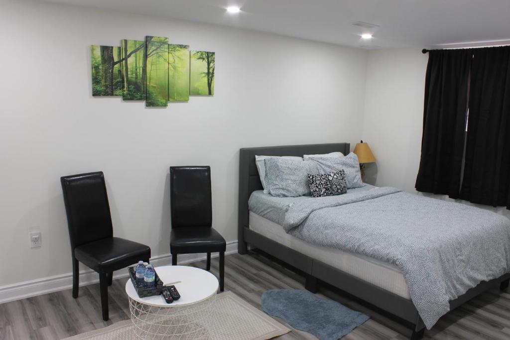 Un dormitorio con una cama y dos sillas. en Comfy basement near KW airport, en Kitchener