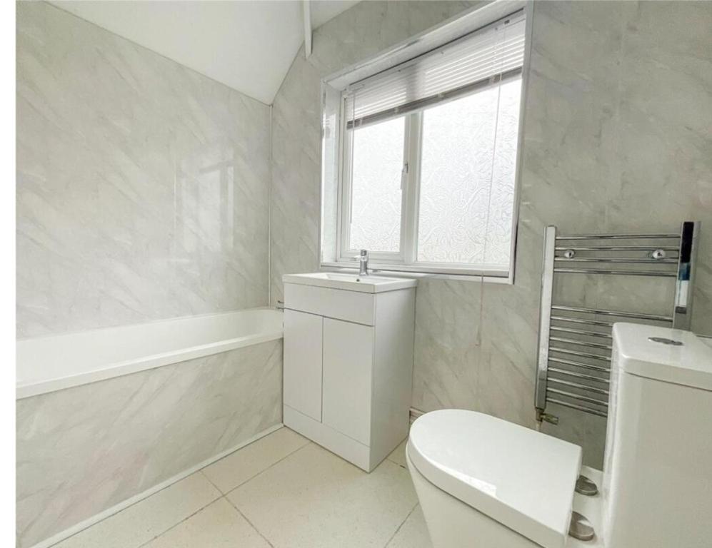 La salle de bains blanche est pourvue de toilettes et d'une fenêtre. dans l'établissement Hardwick house, à Streetly