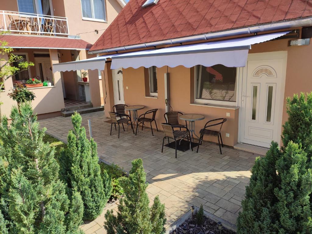 a patio with chairs and tables in a house at Zseli Apartmanház in Siófok