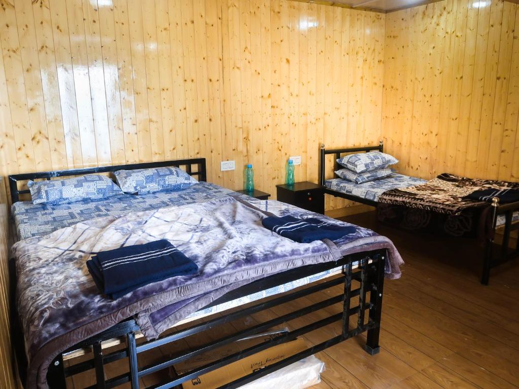 a bedroom with two beds in a room with wooden walls at Homestay Darjeeling in Darjeeling