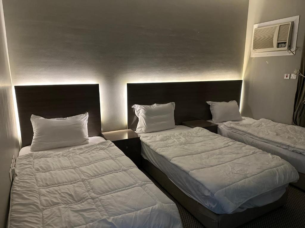 two beds in a hotel room with white sheets and pillows at الجوار in Al Madinah