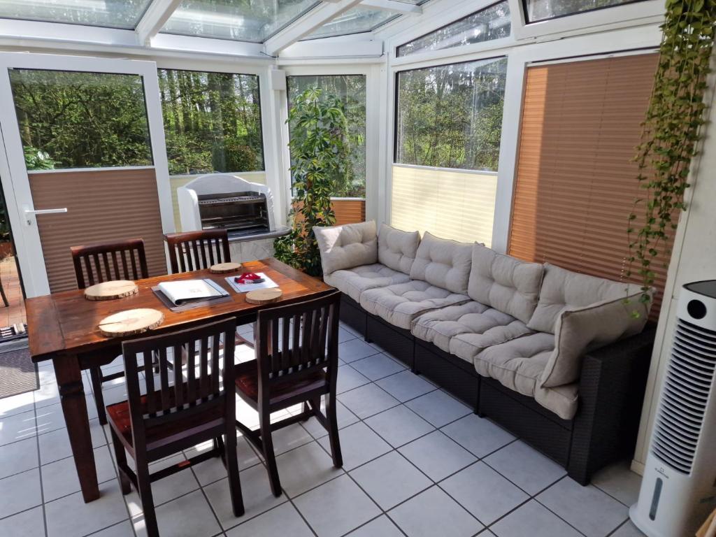 a screened in porch with a couch and a table and chairs at Waldoase im Herzen des Teutoburger Waldes - Handwerker auf Anfrage in Bad Iburg