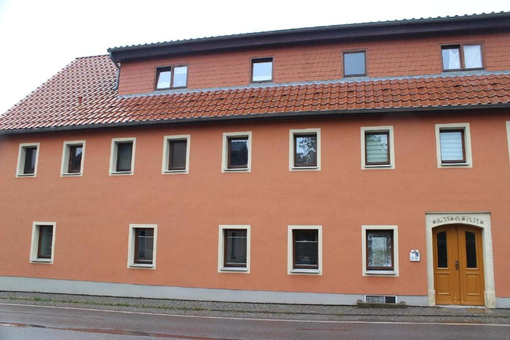 un edificio de ladrillo rojo con puerta naranja en Neue Ferienwohnung in Altendorf mit Garten en Sebnitz