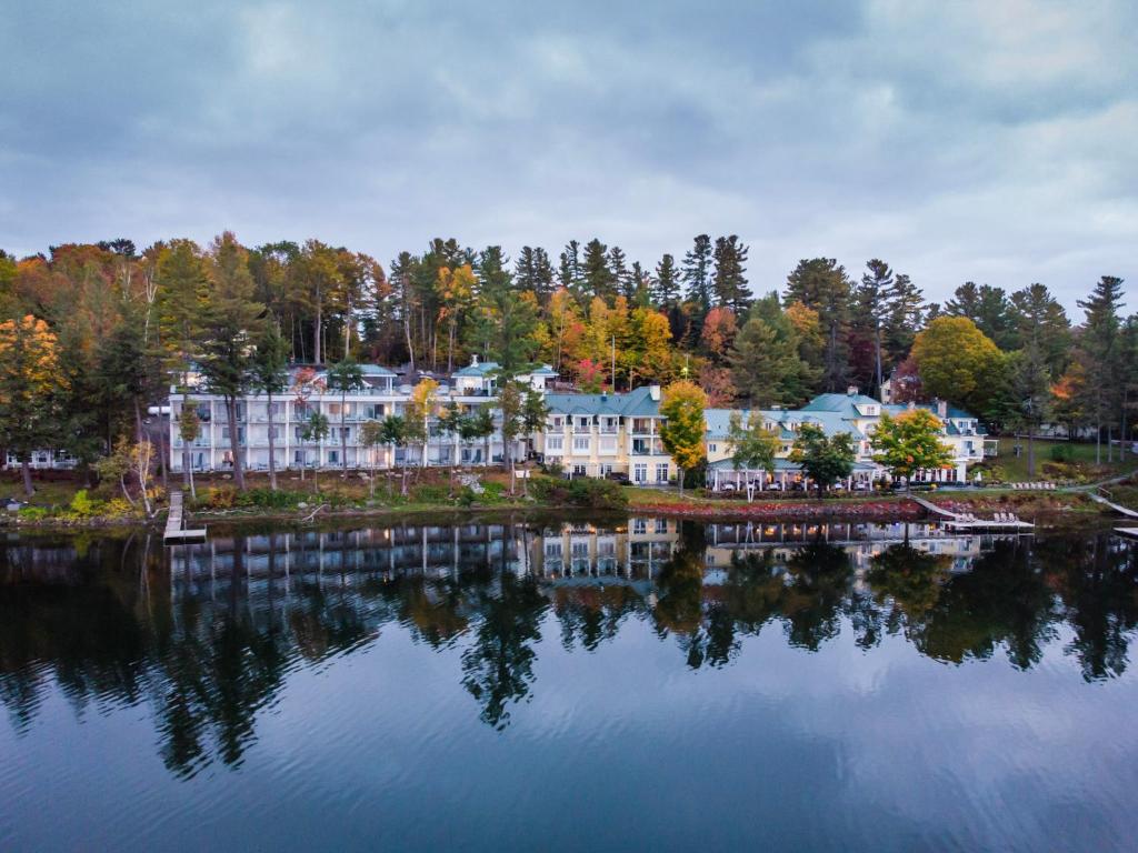 a large resort on a lake with its reflection in the water at Ripplecove Hotel & Spa in Ayers Cliff