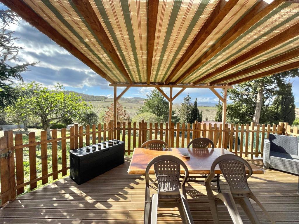 patio ze stołem i krzesłami na drewnianym tarasie w obiekcie GITE DE L'AUXINEILL w mieście Castelnou