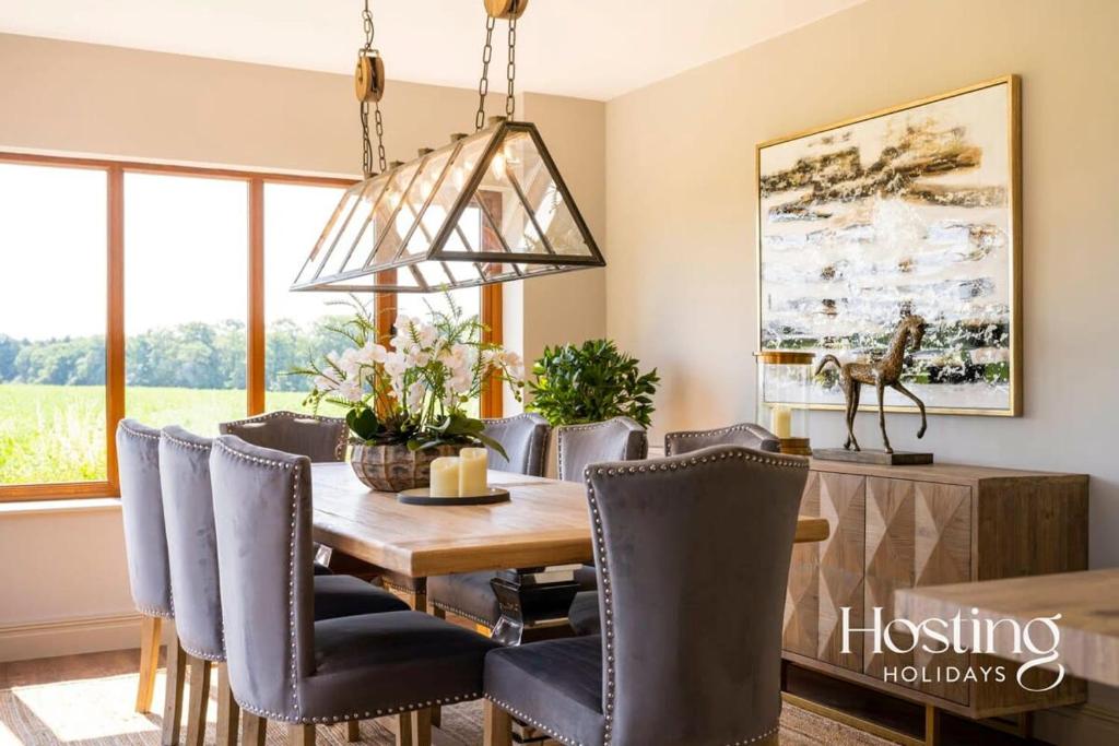 a dining room with a wooden table and chairs at Luxurious 4 Bedroom Villa With Exceptional Views And A Bedroom With A Bath Tub in Twyford