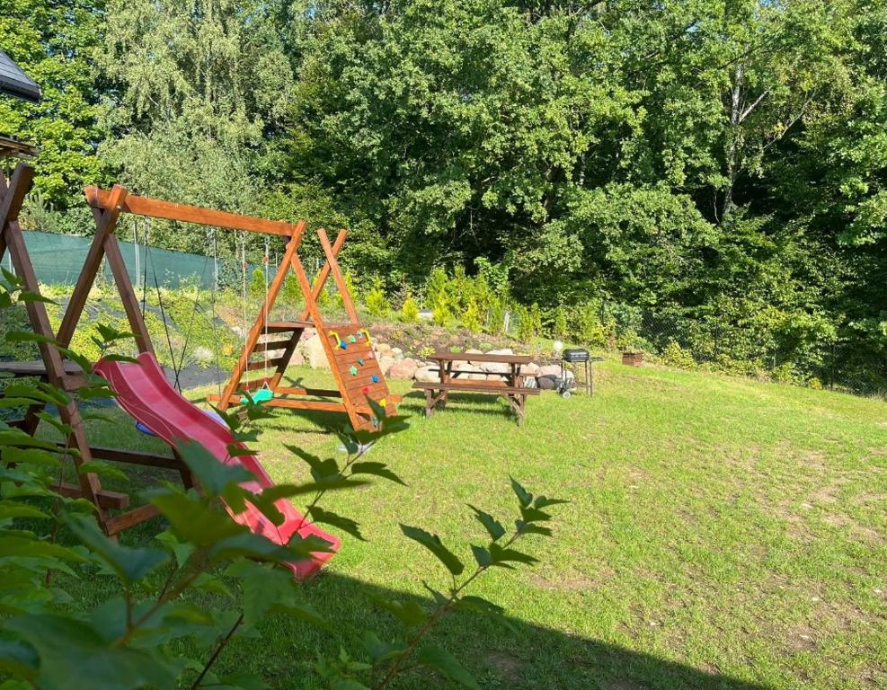 a playground with a swing and a picnic table in a yard at Domek pod Dębami Bogaczewo in Bogaczewo