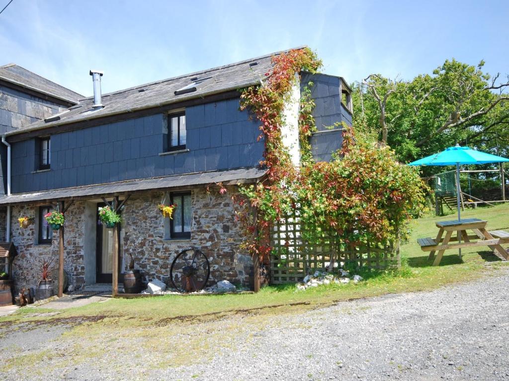 a stone house with a picnic table and an umbrella at 2 Bed in Bude NPHON in Poundstock