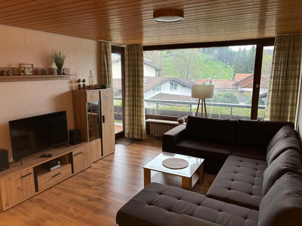 a living room with a couch and a large window at Schöne 2 1/2 Zimmer Ferienwohnung in Oberstaufen - Hoamatle - in Oberstaufen