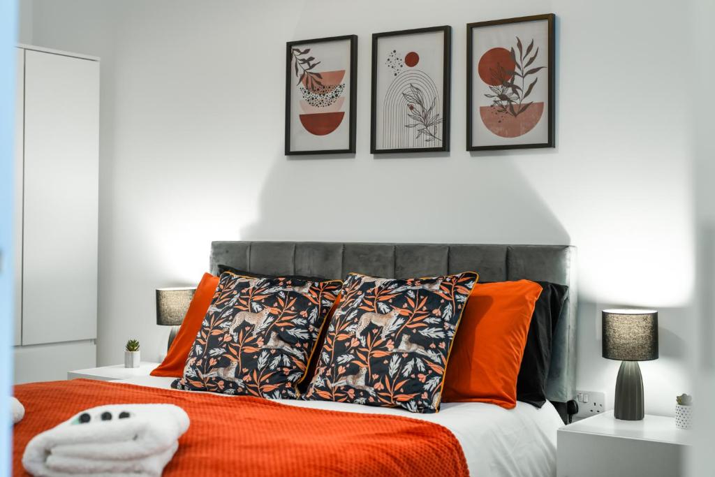 a bedroom with an orange bed with four pictures on the wall at Modern 2 bed in Potters Bar - with FREE Parking- 4 min walk from the TRAIN STATION - DIRECT TRAINS TO LONDON in Potters Bar