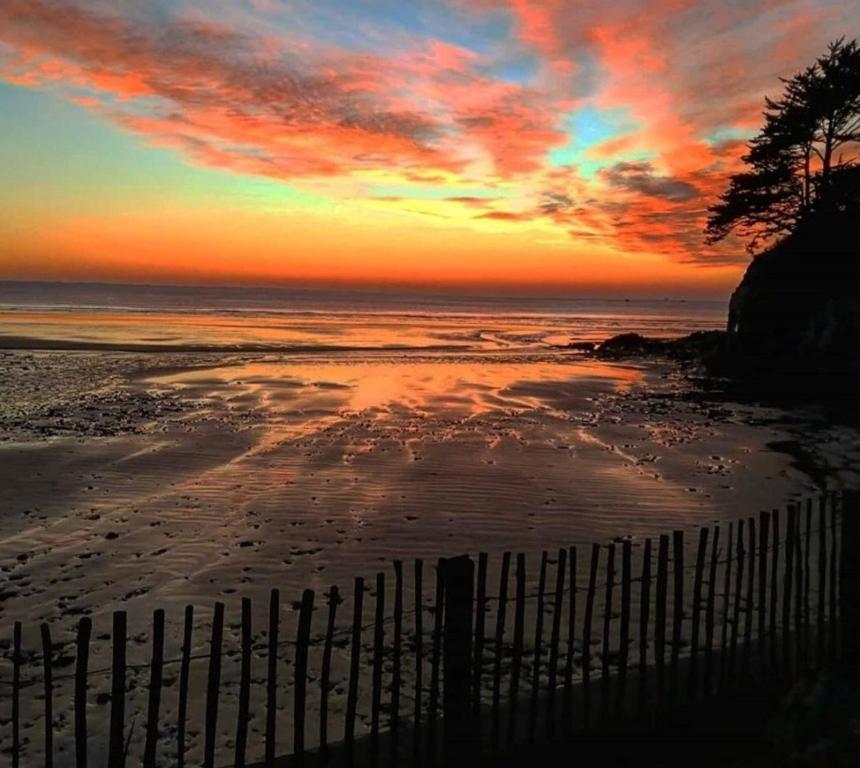 Una puesta de sol sobre una playa con una valla encima en Studio duplex vue mer 100m de la plage, en Saint-Nic