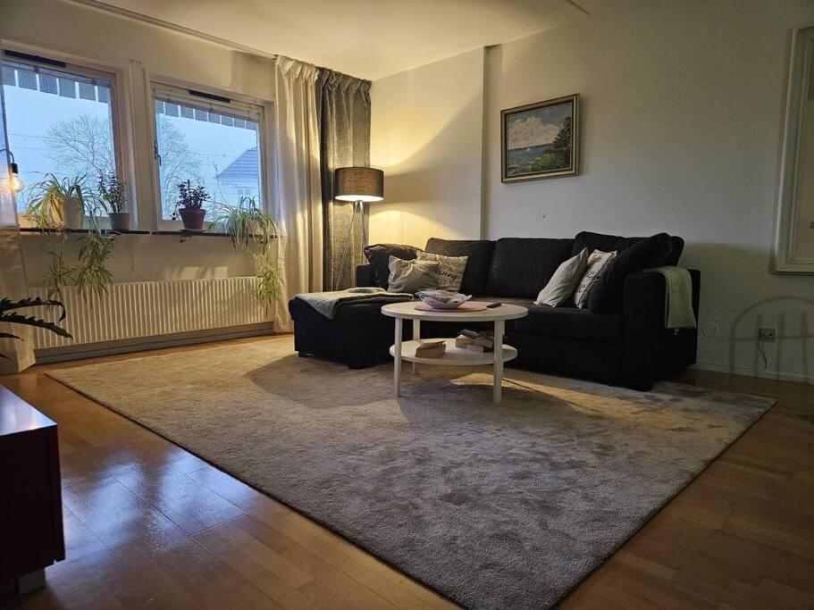 een woonkamer met een zwarte bank en een tafel bij Lägenhet i Älvsborg Göteborg in Göteborg