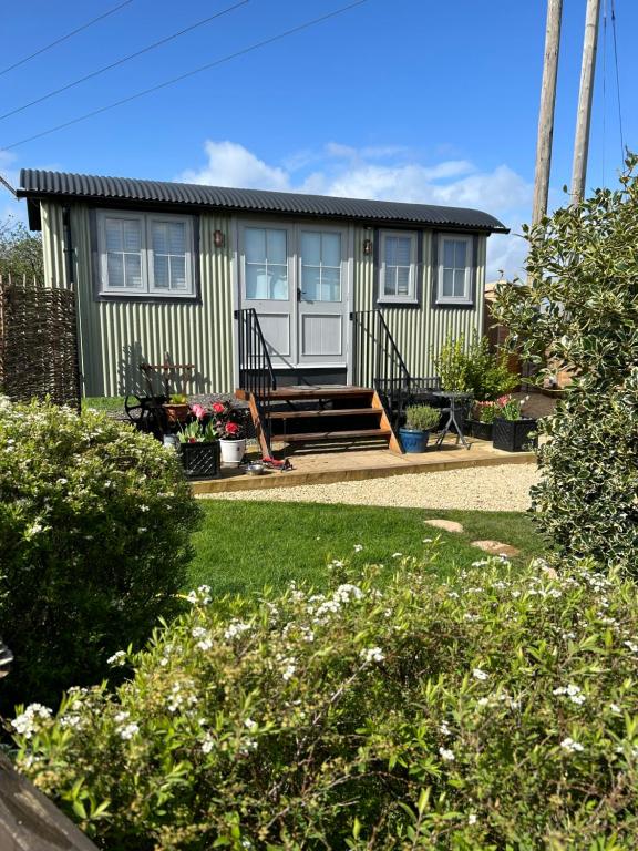 a small green house with a bench in a yard at Cotswold shepherd hut with hot tub and sauna Dog friendly in Charlton