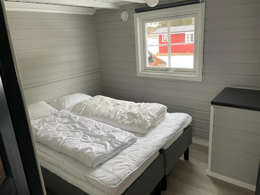 a bed in a small room with a window at Brustranda Fjordcamping in Valberg