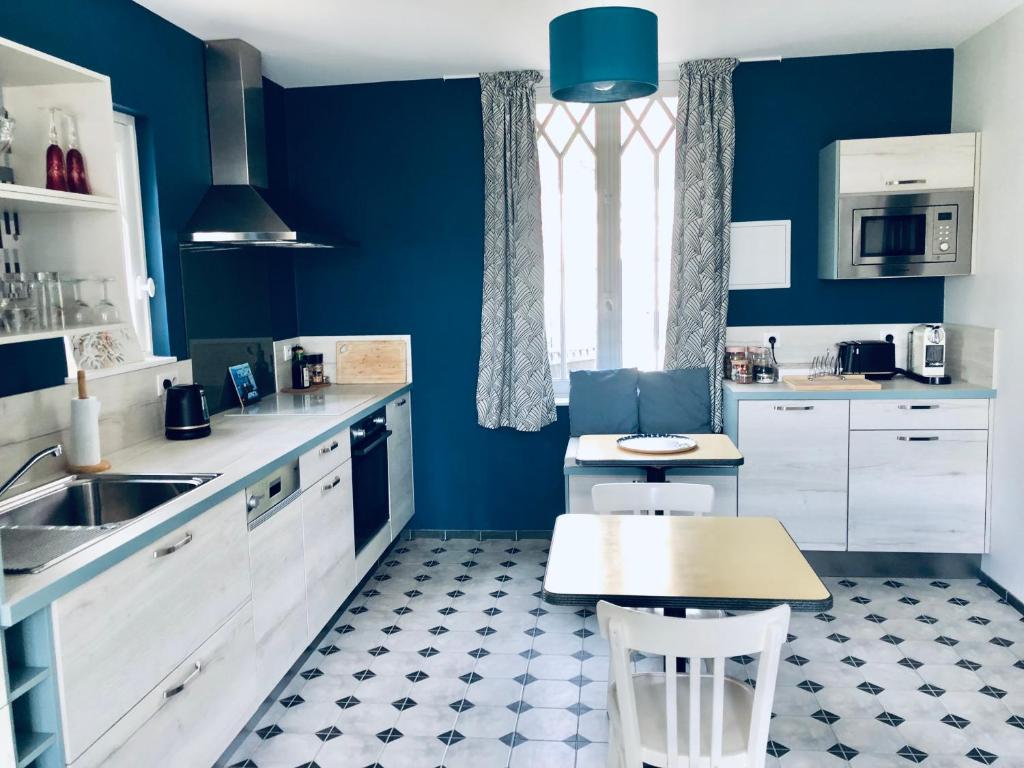 a kitchen with blue walls and white cabinets and a table at Orpheus Lodge in Giverny