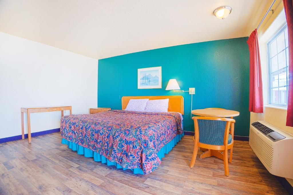 um quarto com uma cama e uma parede azul em Holiday Motel, Lordsburg By OYO em Lordsburg