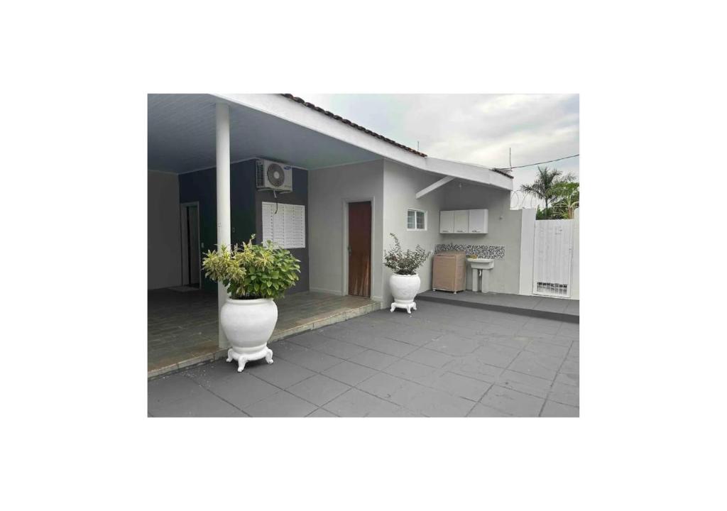 Una casa con dos jarrones blancos con plantas. en kitnet/Loft/Edícula ampla Aracatuba/Birigui, en Araçatuba