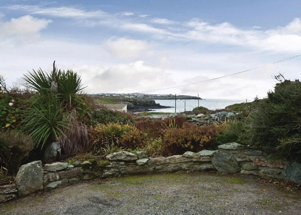 a stone wall with a view of the ocean and a bridge at Anglesey Bungalows in Trearddur
