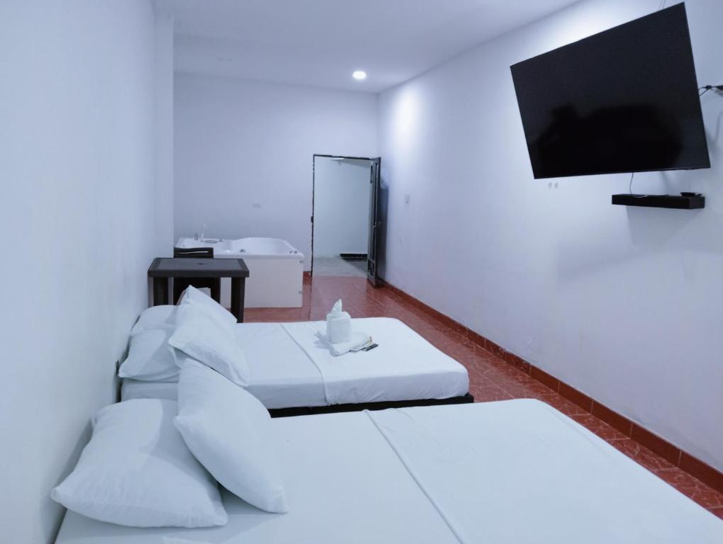 a room with two beds and a flat screen tv at Hostal Martha in Neiva