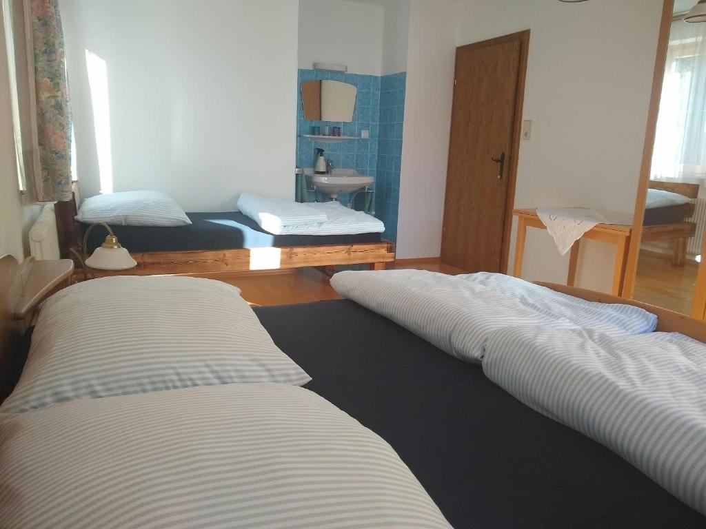 a room with two beds and a bathroom with a sink at Haus Bernkogelblick in Goldegg