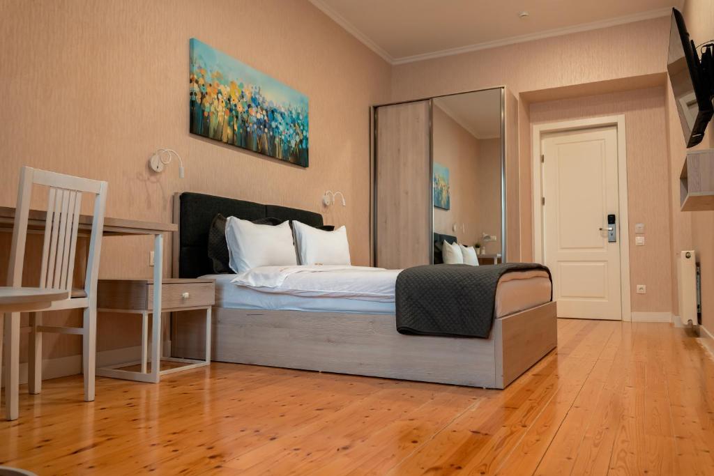 1 dormitorio con cama, escritorio y espejo en Hotel Well Inn, en Tiflis