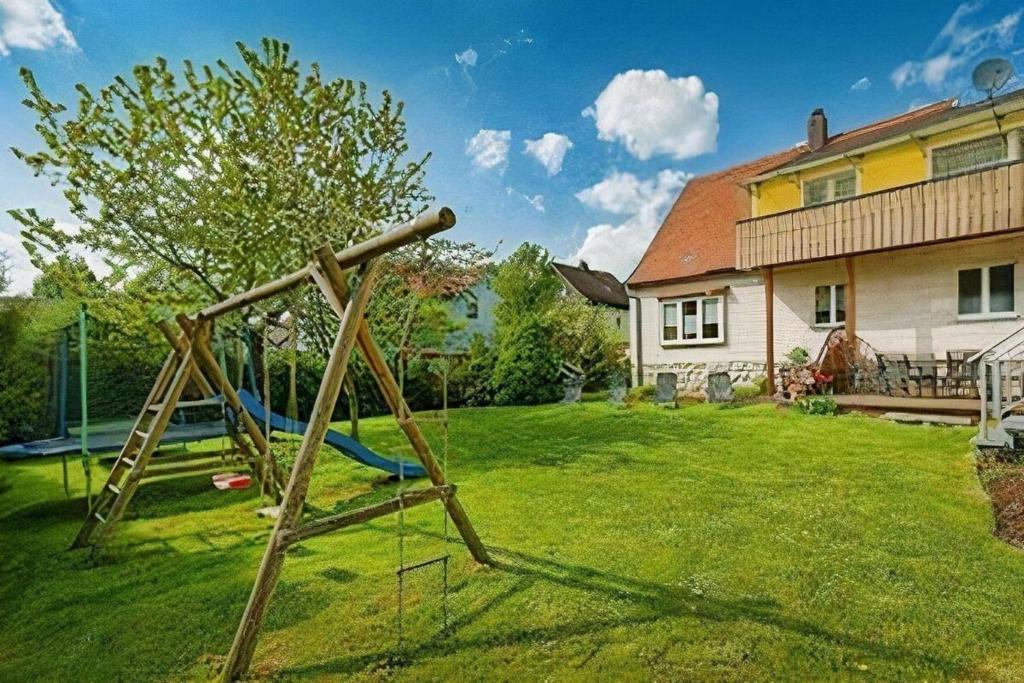 un parque infantil en un patio junto a una casa en Ferienhaus in Bärnau mit Großem Garten, en Bärnau