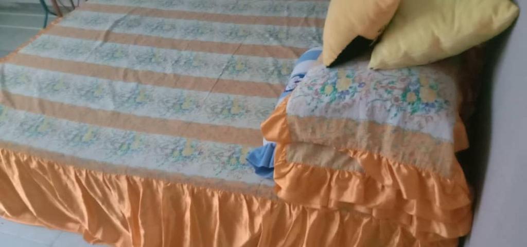 een bed met een oranje sprei bij Sobey Laris Homestay PASIR MAS LATI in Pasir Mas