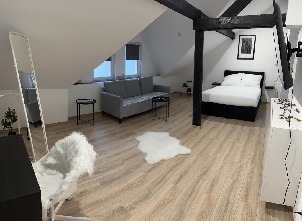 1 dormitorio con cama, sofá y suelo de madera en Modernes Loft am Dreiländereck, en Alsdorf