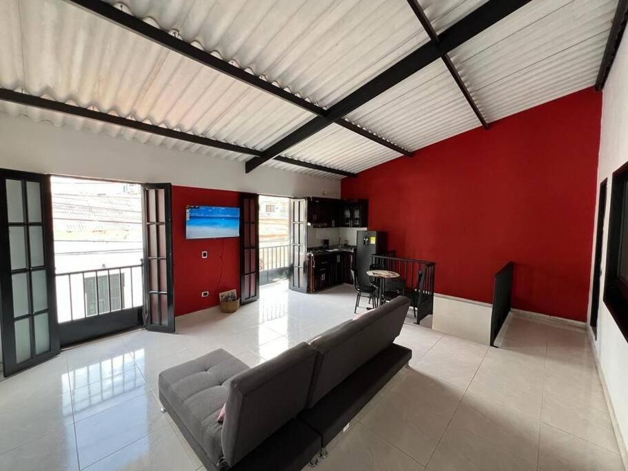 een woonkamer met een bank en een rode muur bij Acogedor apartamento en el centro histórico de Guaduas in Guaduas