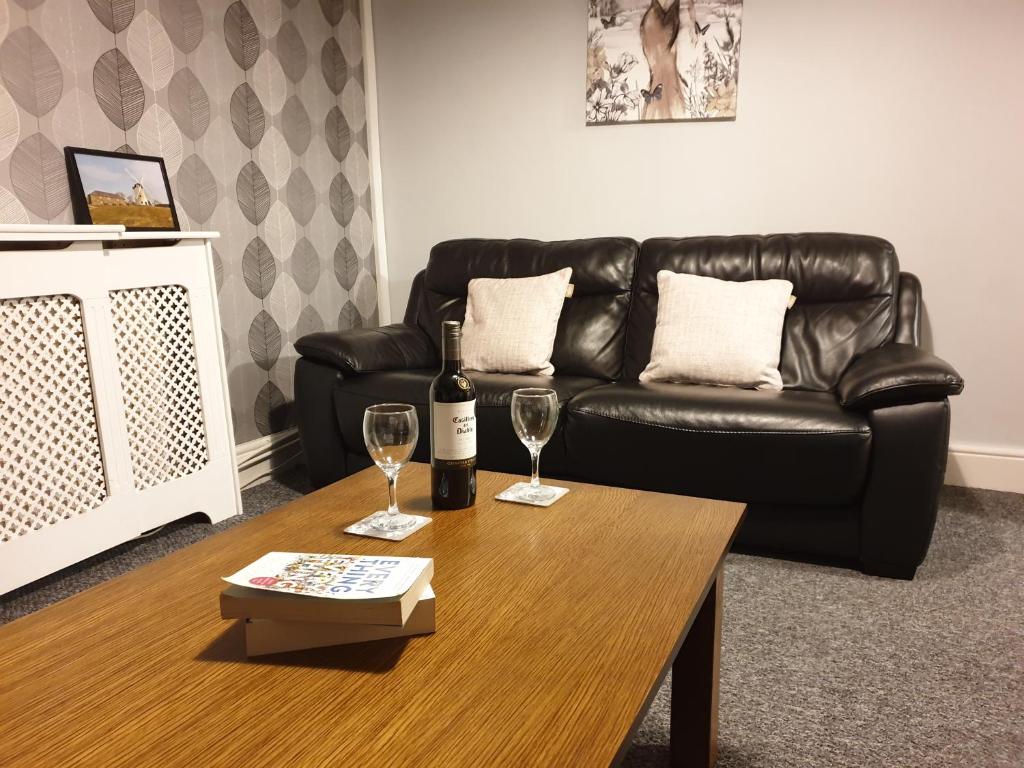 uma sala de estar com um sofá e uma mesa com copos de vinho em Blodfa em Holyhead