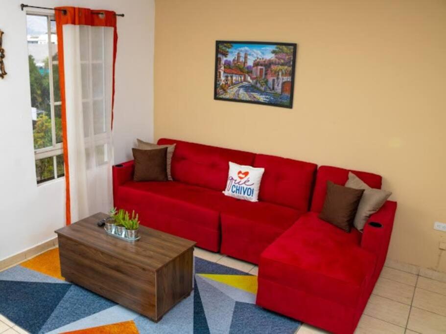 a red couch in a living room with a coffee table at Cozy Two Bedroom Apartment Near The U.S. Embassy in Antiguo Cuscatlán