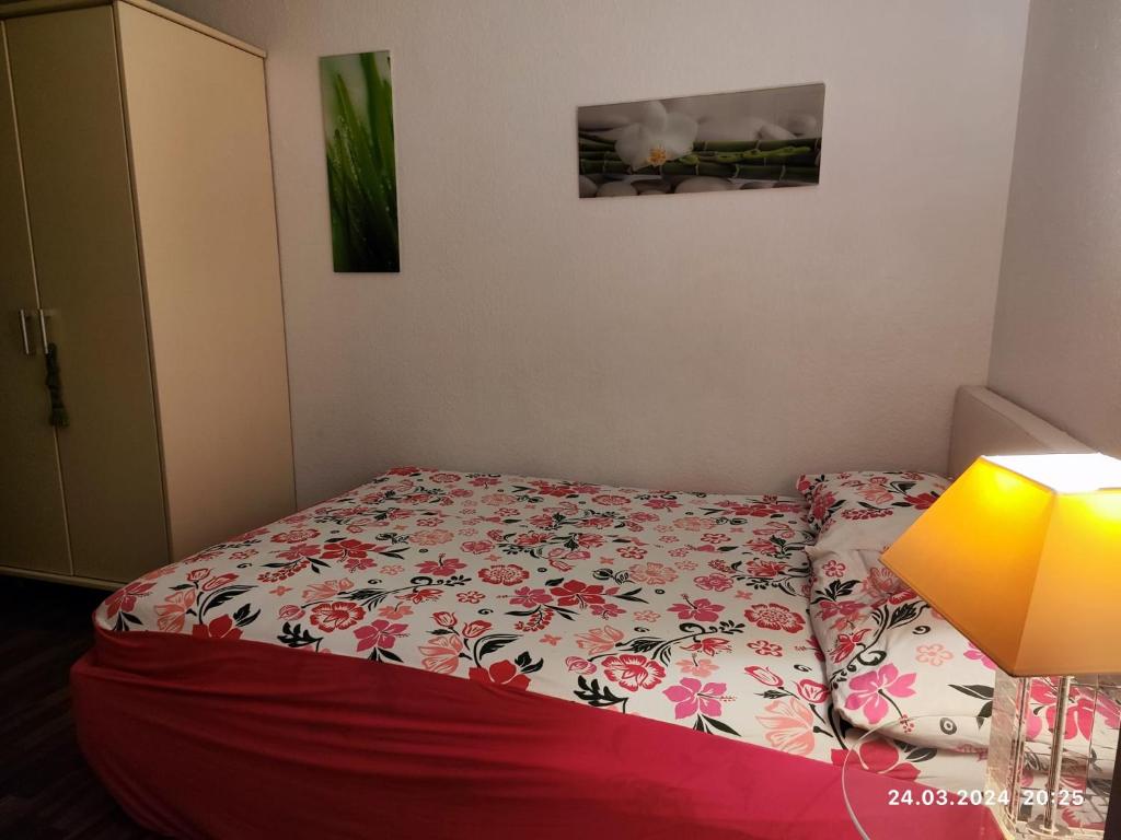 a small bedroom with a bed with a floral bedspread at Altstadt Zimmer in Düsseldorf