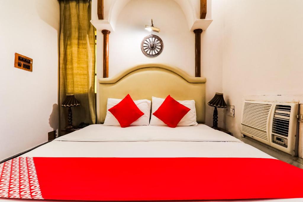 um quarto com uma cama grande e almofadas vermelhas em Resort Sita Kiran em Bareli