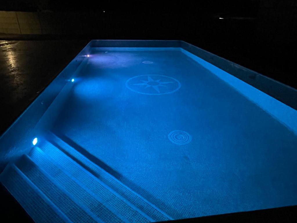 a blue swimming pool with lights in a dark room at Villa Raul in Costinesti