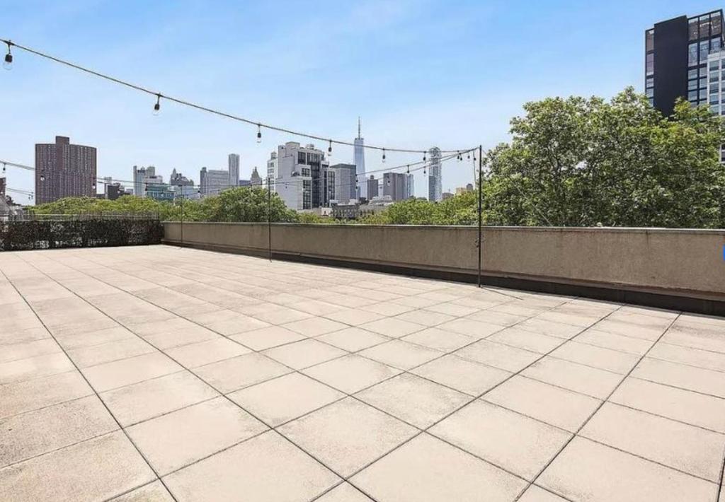 a large patio with a city skyline in the background at Delancey Tower in New York