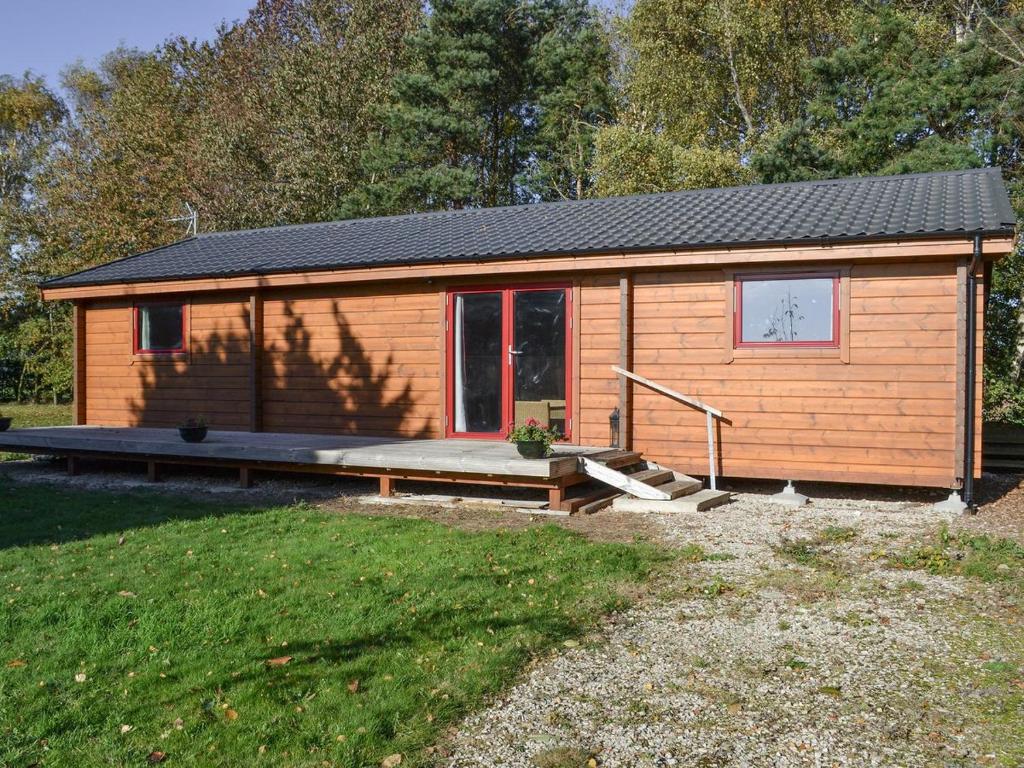 a small wooden cabin with a porch in a yard at Bank End Lodge in Carlton