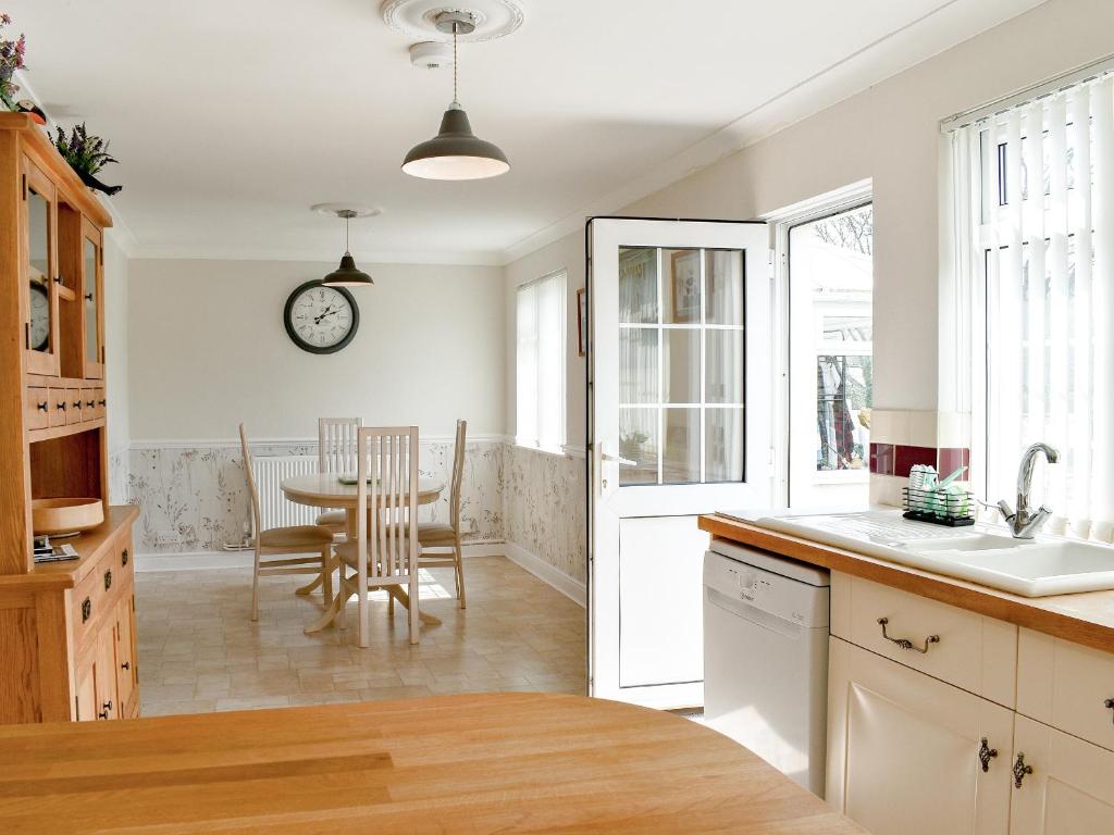 a kitchen with a table and chairs and a clock on the wall at Little Bere in Lifton