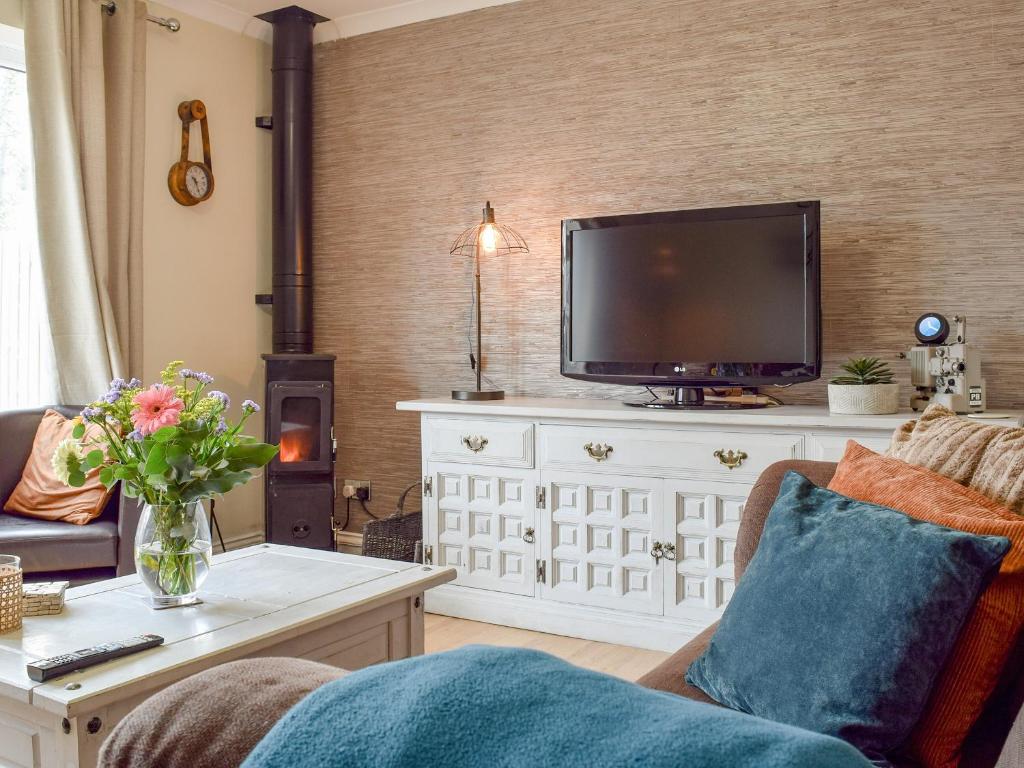 a living room with a tv on a white dresser at Little Lodge in Walcote