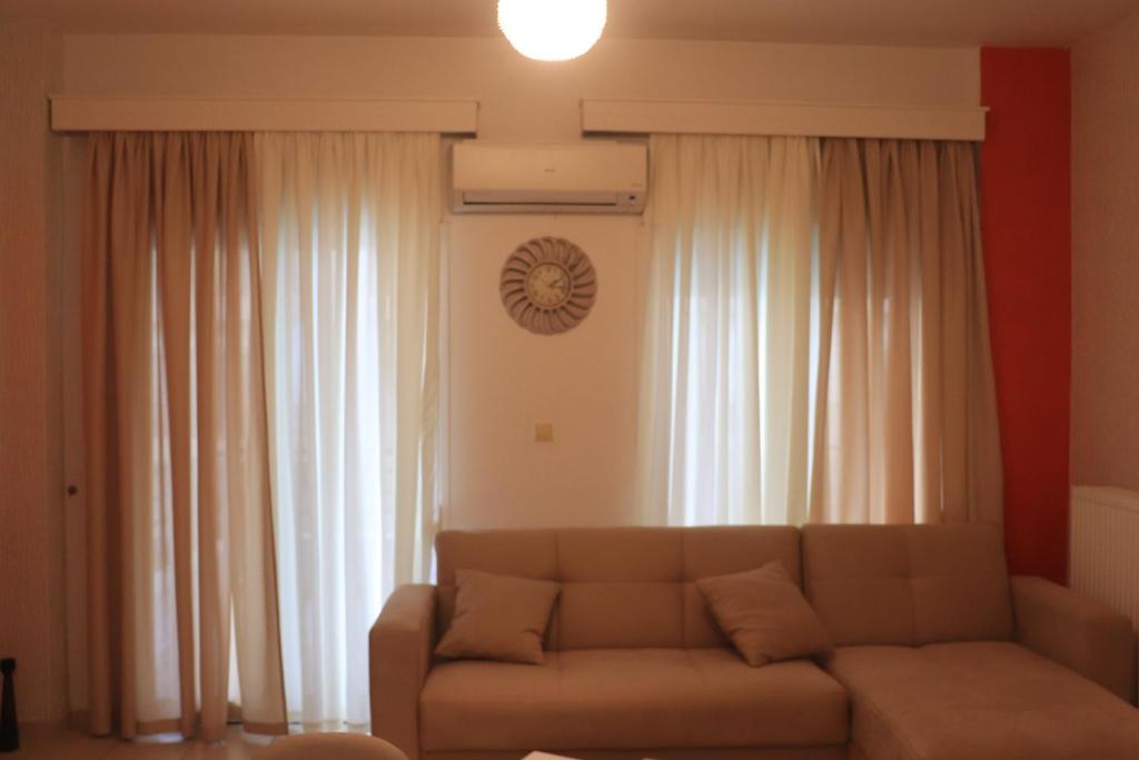 a living room with a couch in front of curtains at Άνετο και όμορφο διαμέρισμα in Xanthi